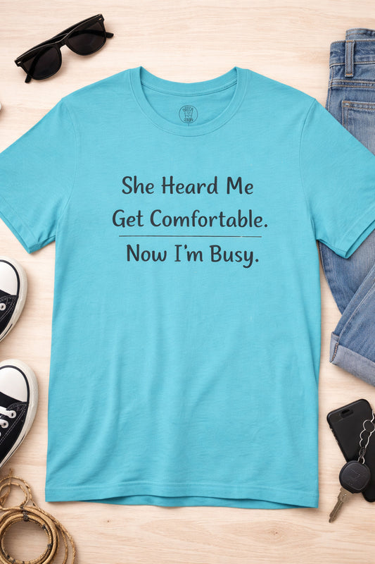 Funny unisex t-shirt with the phrase She Heard Me Get Comfortable Now I'm Busy printed on the front
